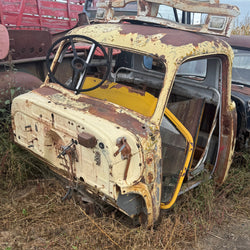 Rust-covered vehicle frame on a trailer in an outdoor setting