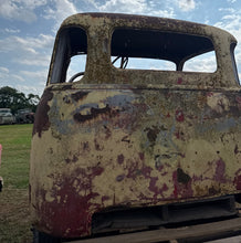 Rust-covered vehicle seat against a blue sky with clouds